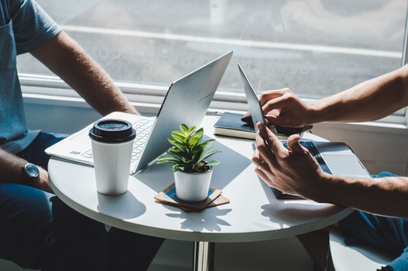 Two people sitting at table with laptops